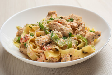 Close Up cajun chicken Fettuccine pasta in a creamy sauce on white plate on wooden table. American cuisine.