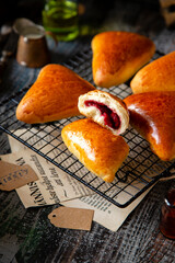 homemade tasty triangle baked sweet buns, piroshki or mini pies with berries filling on wicker metal tray 