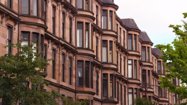 Pan: Large Sandstone Tenements With Enormous Windows Above Lush Green Trees