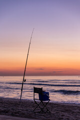Fototapeta na wymiar Fishing rod with sunrise and beautiful colors at malvarosa beach of the City of valencia, costa blanca, spain