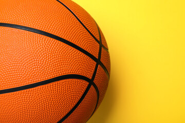 Orange ball on yellow background, top view with space for text. Basketball equipment
