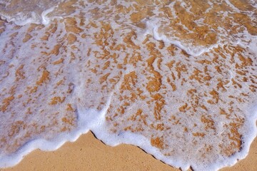 Sand beach with white sea soft foam wave on top view in thailand for assembling an article about travel in summer holiday or ocean sand beach coast nature.