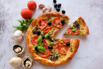  Vegetarian homemade pizza on a light background with a cut piece. Next ingredients -mushrooms, tomatoes, garlic, Basil, olives.   The concept of healthy eating.