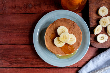 Home-made banana pancake on a blue plate. Eat with maple syrup or honey and fresh fruit. The concept of healthy homemade food. Copy space