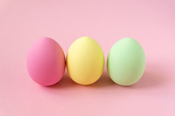 Three multicolored easter painted eggs on pink background