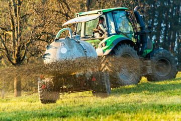 Landwirt auf Weide mit Traktor und Güllefass beim düngen im Frühjahr © JM Soedher