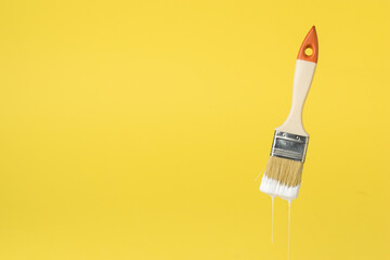 Brush with dripping white paint on a white background. Space for the text.