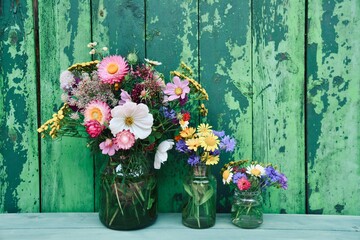 Bouquet of wild flowers in front of a rustic green wooden background - concept for birthday, mother's day and home decoration - seasonal greeting card