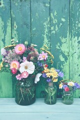 Bouquet of wild flowers in front of a rustic green wooden background - concept for birthday, mother's day and home decoration - seasonal greeting card