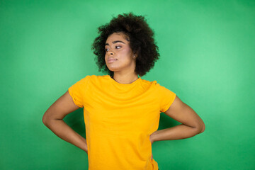 African american woman wearing orange casual shirt over green background with a happy face standing and smiling with a confident smile showing teeth