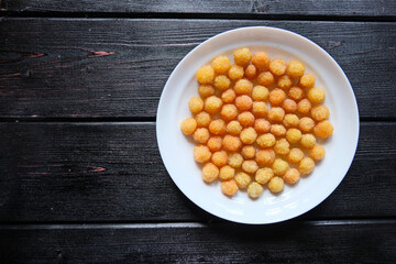 Ripe yellow raspberry lies on a white plate on a black background. Top view. Copy space.