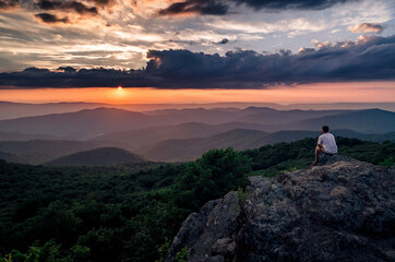 A hiker enjoying a Summer sunset from Bearfence Mountain in Shenandoah National Park.