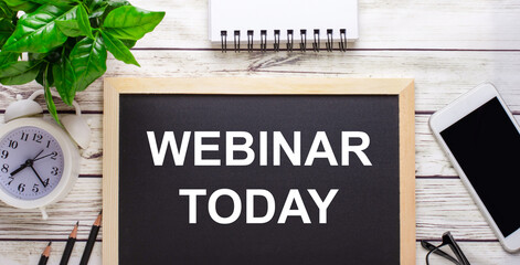 WEBINAR TODAY written on a black background near pencils, a smartphone, a white notepad and a green...