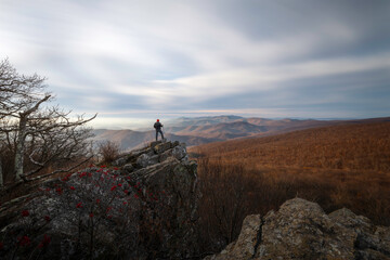 A hiker overlooking an overcast scene in Shenandoah National Park during a snowless period of Winter.