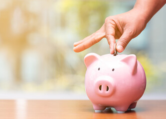 Concept hand putting money coin into piggy bank saving money for future plan and retirement fund,...
