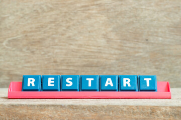 Obraz premium Tile alphabet letter with word restart in red color rack on wood background