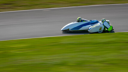 A panning shot of a racing sidecar as it corners on a track.