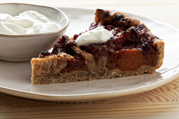 Piece of quince stuffed pie served with yoghurt. Close-up view of homemade dessert.