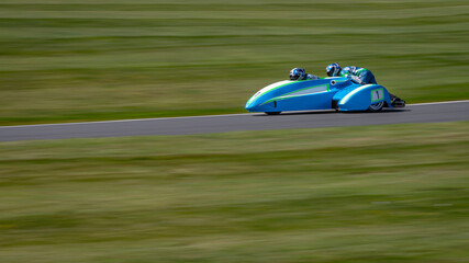 A panning shot of a racing sidecar as it corners on a track.