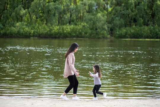 Happy young mother playing together with her adorable little daughter in beautiful scenic spring landscape
