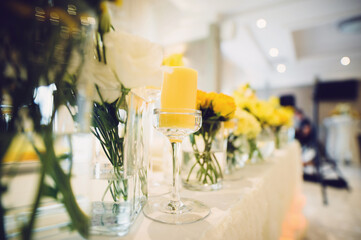 candle in glass on table with flowers