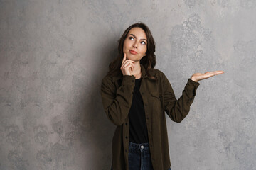 Thinking beautiful brunette girl looking upward and holding copyspace