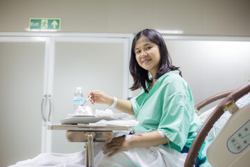 Obraz premium Happy female Patient Enjoying Meal In Hospital Bed