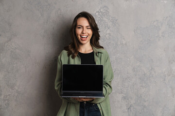 Happy beautiful nice girl smiling and winking while showing laptop