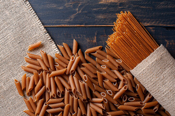.Raw wholemeal pasta, spaghetti, and penne. Top view. Copy space