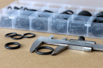 Measuring the diameter of the rubber O-ring with a caliper. An old measuring tool and a set of sealing gaskets for pneumatics and hydraulics.
