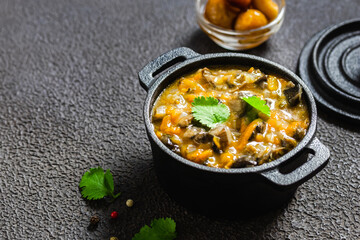 Hearty vegan lentil mushroom stew in cast iron pot. Space for text.