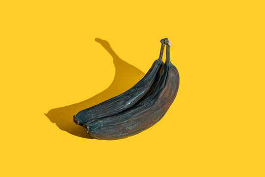 Old Shriveled Blackened Bananas On Yellow Background