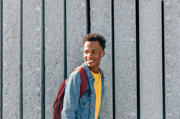 Happy black boy listens to music on the street © Óscar