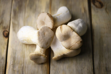 Raw eringi mushrooms on a wooden surface.
