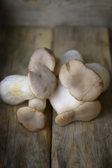 Raw eringi mushrooms on a wooden surface.