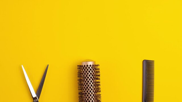 Stop motion animation template flat lay of professional hair cutting shears comb for separating hair and gold round hair brush for styling on yellow background Hairdresser salon equipment concept