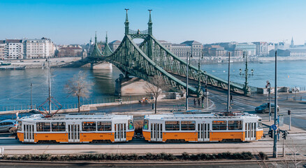 Fototapeta na wymiar A yellow tram on the Danube embankment . Freedom Bridge in Budapest, Hungary. Sunny view. 