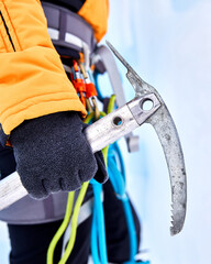 Woman climber holding ice axe in the mountains