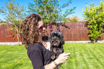 Junge Frau hält ihren schwarzen Bichon Hund auf dem Arm