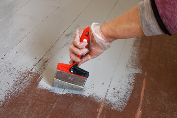Malowanie starej podłogi z desek na kolor jasnoszary.