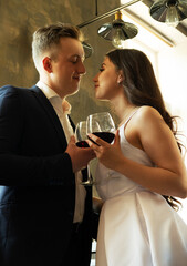 Young newlywed couple drinking wine and smiling at their happiness, romance and tenderness.
