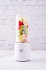 Mixed fruit, apple, kiwi, banana and strawberry in portable blender ready to make smoothie