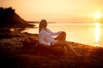 blonde girl in a white man's shirt on the riverbank, selective focus