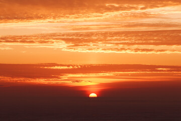 late beautiful sunset with clouds, sun goes down behind dark horizon, natural beauty background