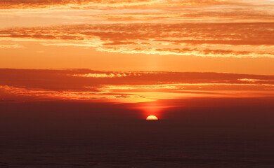 late beautiful sunset with clouds, sun goes down behind dark horizon, natural beauty background