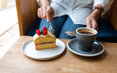 Closeup image of a woman eating cake and drinking coffee in cafe