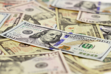 a hundred dollar bill with a franklin lies on other bills, blurred background, close-up