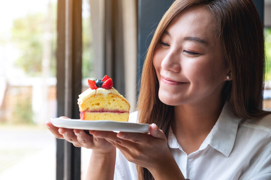 Closeup image of a beautiful young asian woman holding a piece of cake in a plate