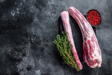 Fresh Raw whole Beef veal Oxtail Meat on marble board with herbs. Black background. Top view. Copy...