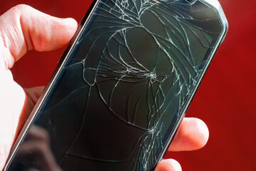 broken phone in hand on red background